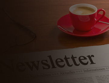 Copy of newsletter on desk with eye glasses and mug of coffee