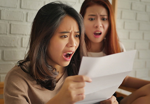 Two women looking at a piece of paper in shock