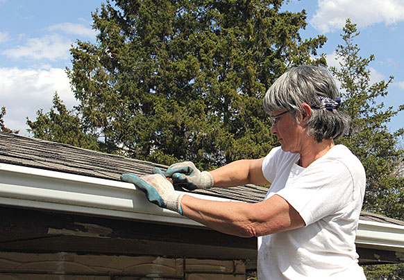 Woman working on home gutters