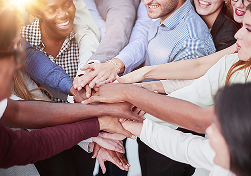 Group of people in a circle placing their hands on top of each other.