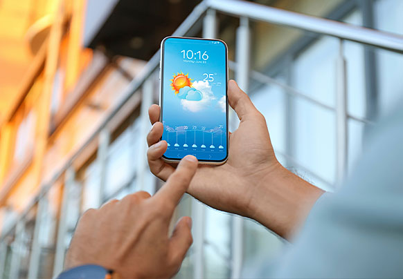 Hands holding a phone with a weather forecast displayed